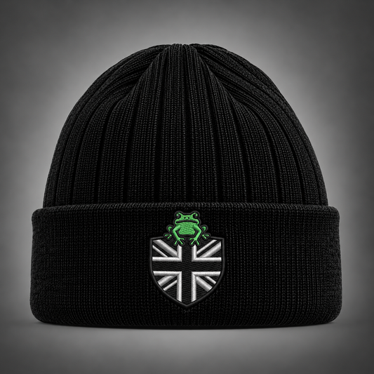 A black ribbed knit beanie hat with a folded cuff, featuring an embroidered shield patch with a Union Jack design and a green frog emblem on top, set against a dark gray gradient background.